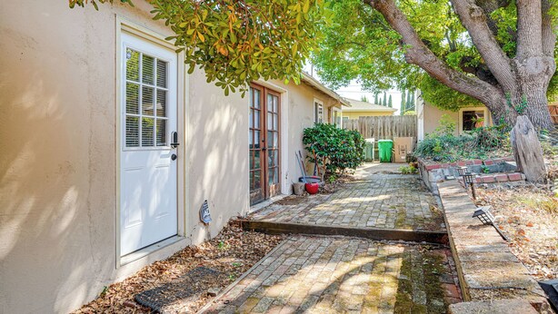 A residential property with a paved driveway, a white door, and a small garden area with a tree and a wooden fence. - Serene Studio in SF Suburbs: Quiet + Cat Friendly! (Castro Valley)