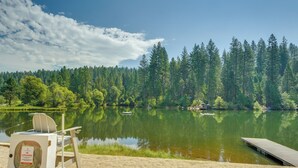 A lifeguard chair and a dock by a calm lake with a forest backdrop. - Sleek Blue Lake Springs Retreat w/ Deck & Yard! (Arnold)