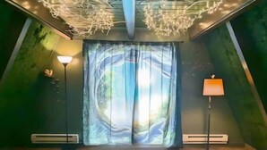 A room with a large window, a floor lamp, a table lamp, and a ceiling light fixture. - Enchanted Forest 2-Story Villa (Ocean Shores)