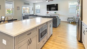 Una cocina moderna con una isla, horno empotrado y un televisor de pantalla plana grande.