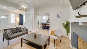 Een woonkamer met een bank, salontafel en een aan de muur bevestigde televisie.