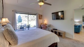 A bedroom with a large bed, a ceiling fan, a TV, a desk, and a chair. - Pet-Friendly Stay w/ Patio in Palm Desert Resort! (Palm Desert)