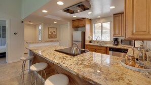 A kitchen with a marble countertop, stainless steel appliances, wooden cabinets, and a bar stool area. - Pet-Friendly Stay w/ Patio in Palm Desert Resort! (Palm Desert)