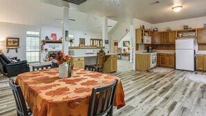 A spacious kitchen with wooden cabinets, a dining area with a table covered in a patterned tablecloth, and a ceiling fan. - Relax By the Lake: Quiet East Texas Retreat (Warren)