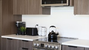 Una cocina moderna con armarios de madera, estufa integrada, microondas y hervidor sobre la encimera.