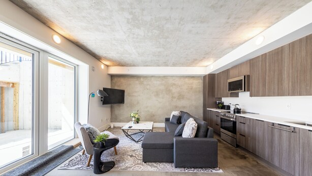 Una sala de estar moderna con un sofá, una mesa de centro y un televisor montado en la pared.