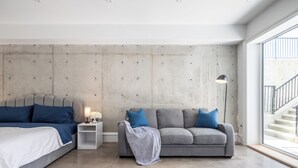 Un dormitorio moderno con una cama, un sofá gris y una mesita de noche.
