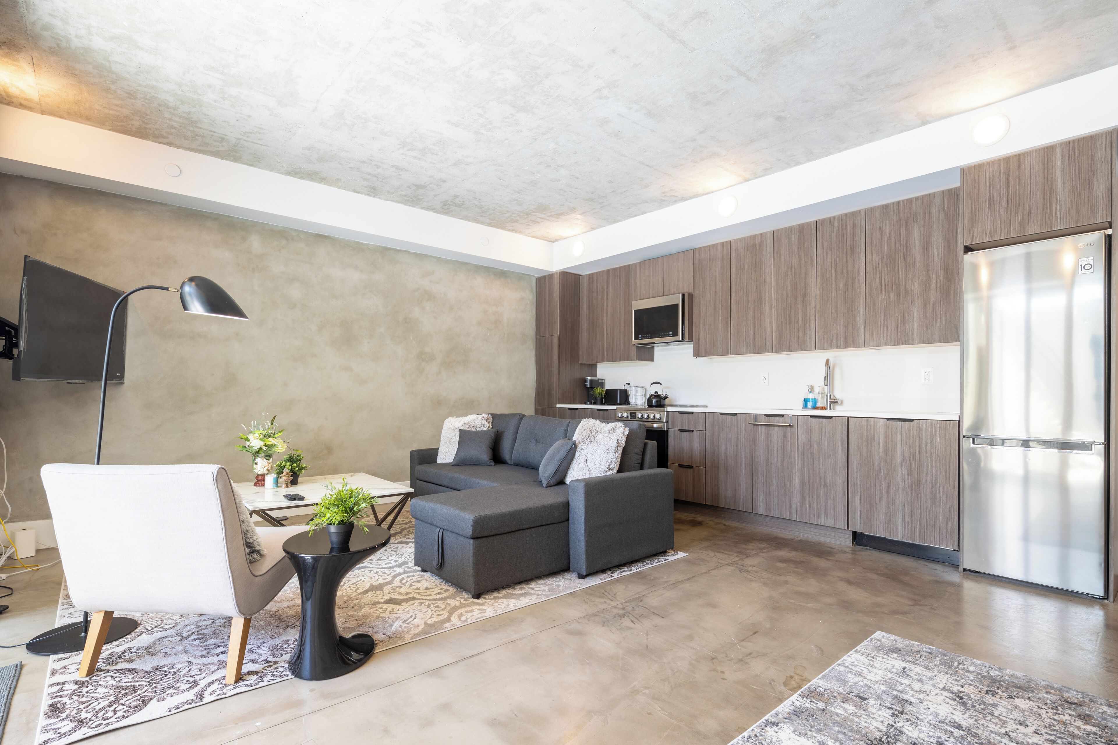 A modern kitchen with a built-in microwave, a stainless steel refrigerator, and wooden cabinets.