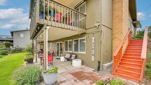 A two-story building with a covered patio area, outdoor seating, and a wooden staircase.