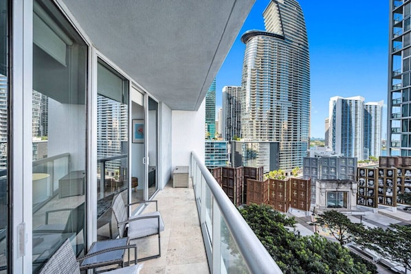A balcony with a city view, a glass door, and a small seating area.