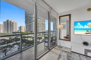A modern apartment with large windows, a balcony, a TV, and a city view.