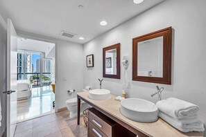 Ein modernes Badezimmer mit einem groĂen Spiegel, zwei Waschbecken und einer Toilette.