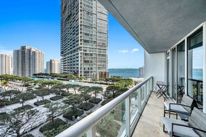 A high-rise building with a balcony overlooking a pool area and ocean view.