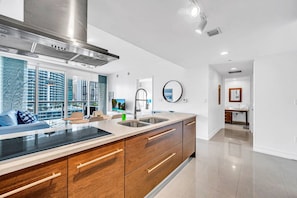 A modern kitchen with a large island, stainless steel appliances, and a view of high-rise buildings.