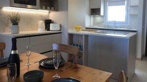Une cuisine moderne équipée d’un four à micro-ondes encastré, d’une machine à café et d’un petit îlot central avec un évier.