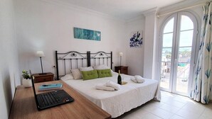 Une chambre d’hôtel avec un lit, un bureau avec un ordinateur portable, une bouteille de champagne et une vue sur la ville par la fenêtre.