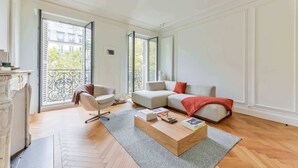 Amplia sala de estar con un ventanal grande, un sofá, una mesa de centro y una silla.
