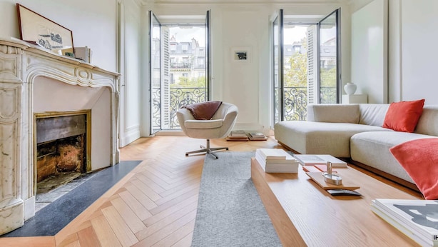 Una sala de estar con chimenea, un sofá, un sillón y vistas a la ciudad a través de puertas abiertas.