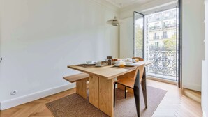 Un comedor con una mesa de madera, sillas y un banco. Se ve una ventana con balcón.