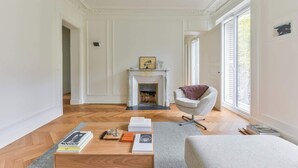 Un salón espacioso con chimenea, un sillón cómodo y una mesa de centro con libros y un control remoto.