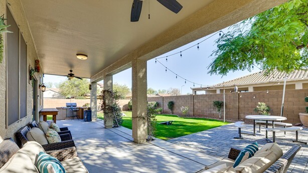 A covered patio area with outdoor seating, a grill, and a lawn. - Spacious 5-bedroom house 3 min from Cardinals Stadium and West Gate shopping (Phoenix)