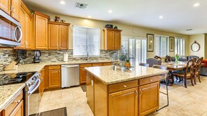 A spacious kitchen with wooden cabinets, granite countertops, and a central island. - Spacious 5-bedroom house 3 min from Cardinals Stadium and West Gate shopping (Phoenix)