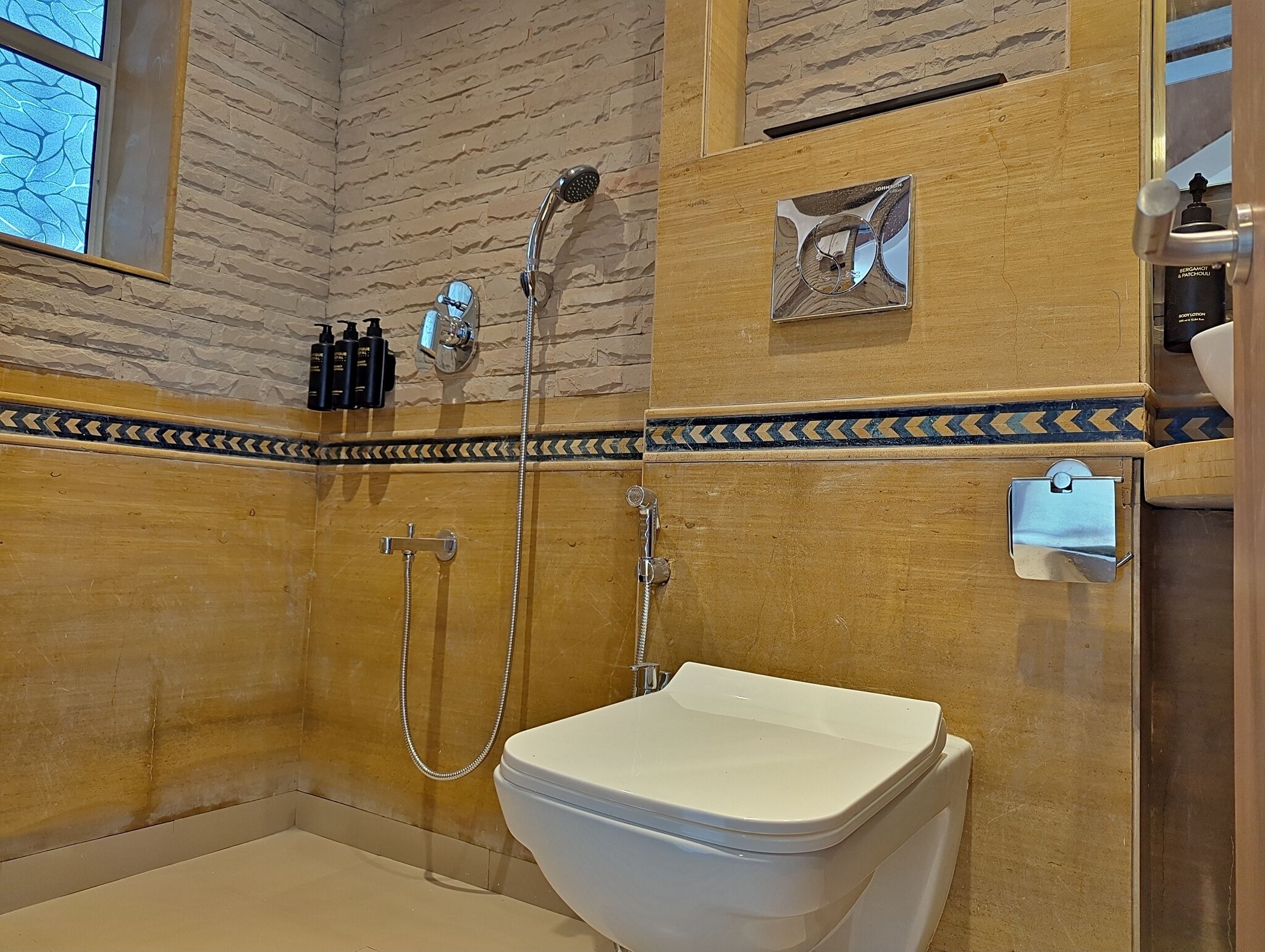 Une salle de bain équipée d’une douche, de toilettes et d’un miroir sur lequel est accrochée une serviette.