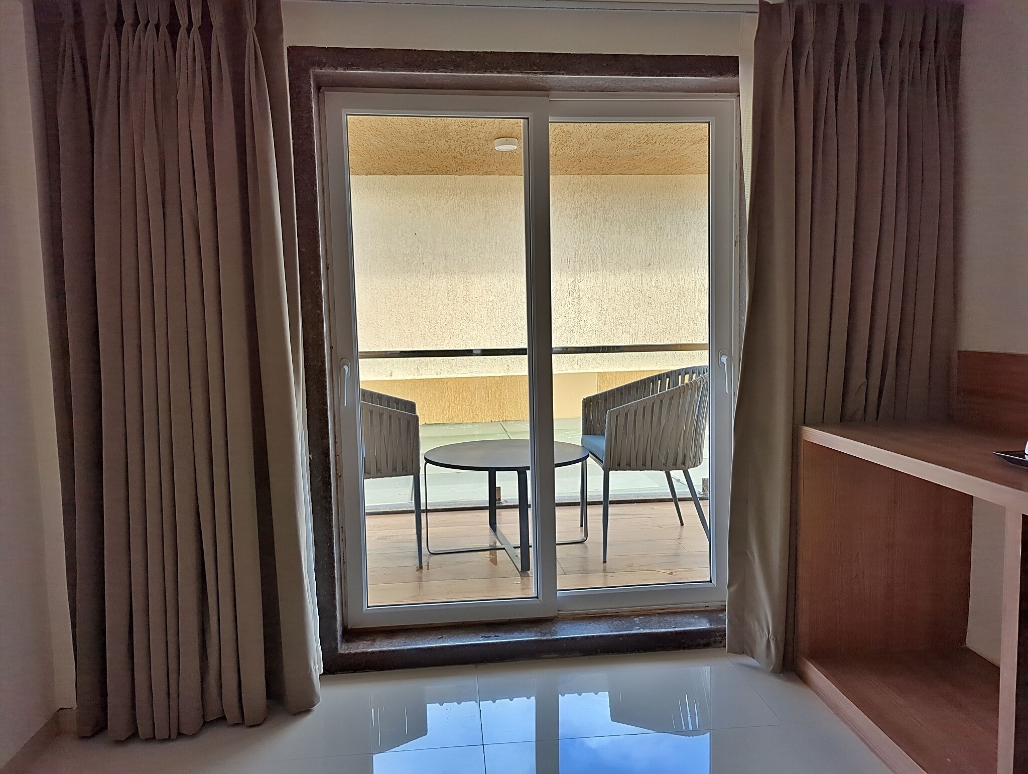A room with a sliding glass door leading to an outdoor balcony with a table and chairs.