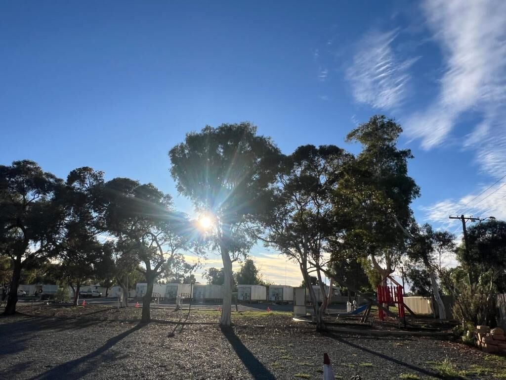 Un parque con árboles, un área de juegos y un cielo despejado.