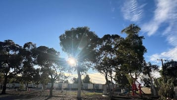 Un parque con árboles, un área de juegos y un cielo despejado.