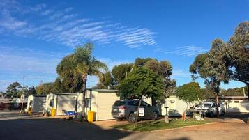 A caravan park with multiple caravans parked in rows, surrounded by trees and a clear blue sky.