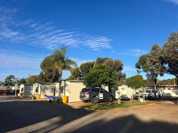 A caravan park with multiple caravans parked in rows, surrounded by trees and a clear blue sky.