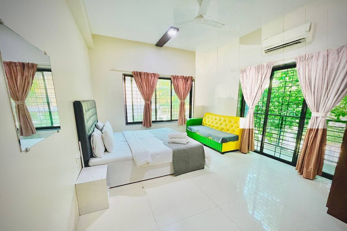 A bedroom with a bed, a sofa, and a window with curtains.