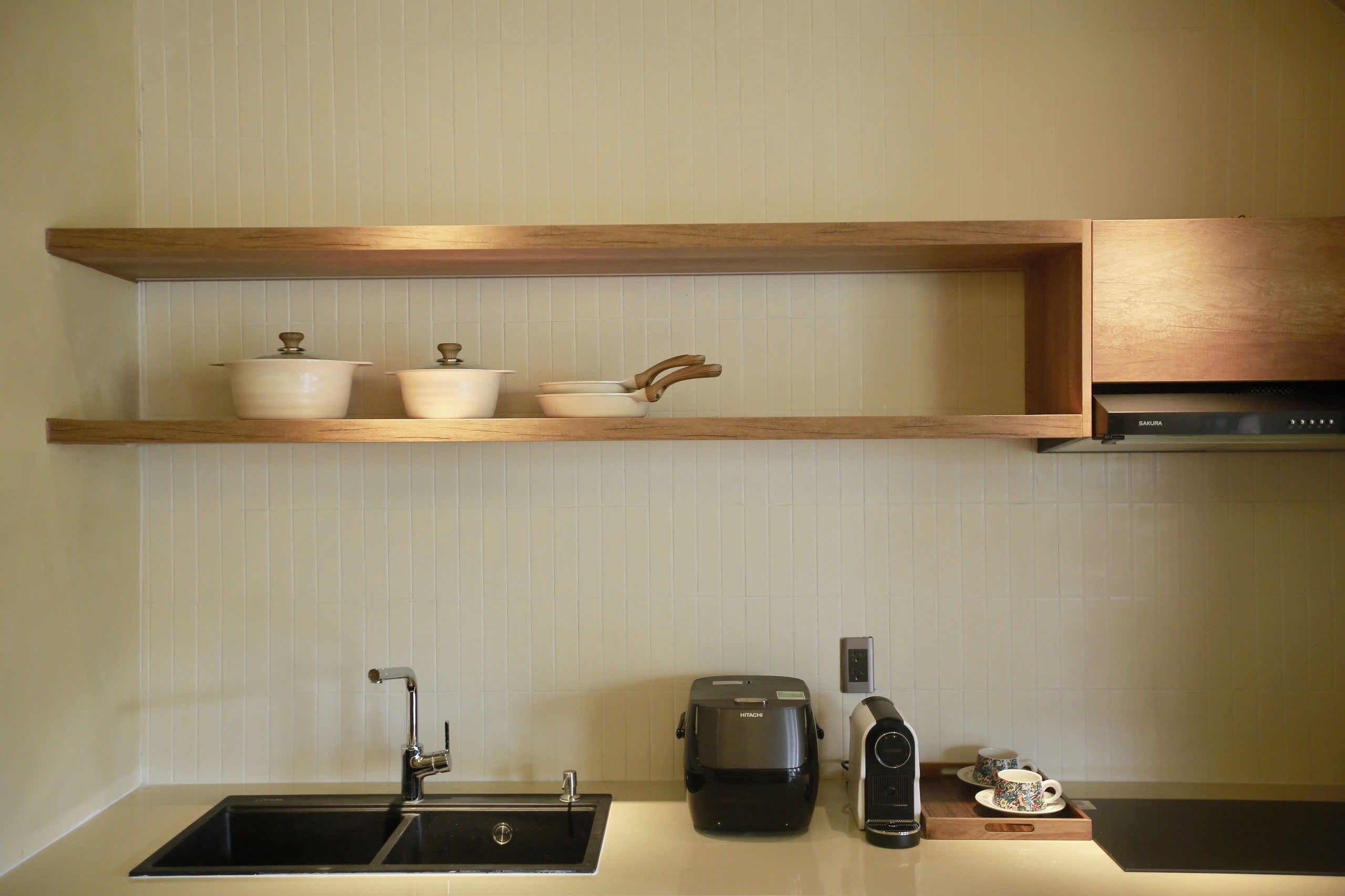 A kitchen with a double sink, a coffee maker, a rice cooker, and a shelf with pots and pans.
