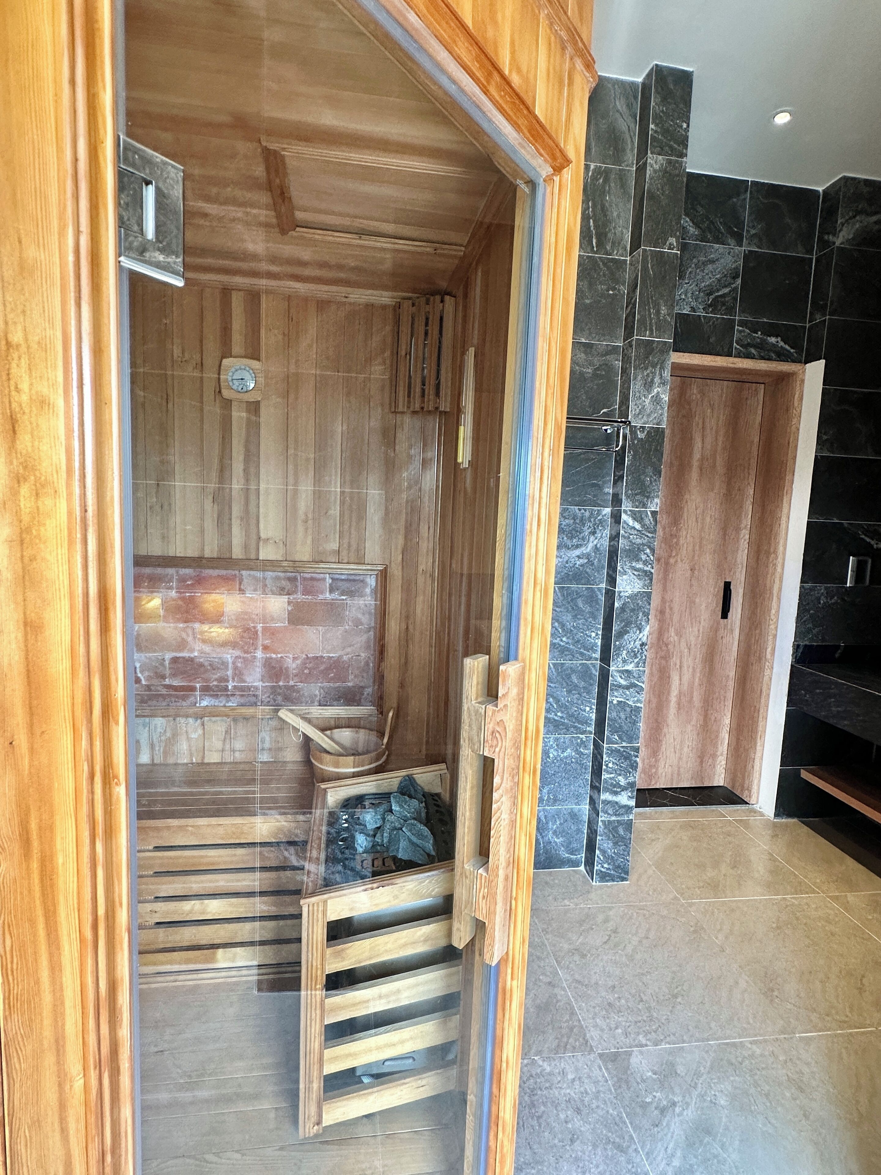 Un sauna avec des bancs en bois et un mur en pierre.