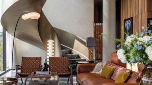Un salon moderne avec un escalier à volutes, un canapé en cuir, une table basse en bois et un vase rempli de fleurs.