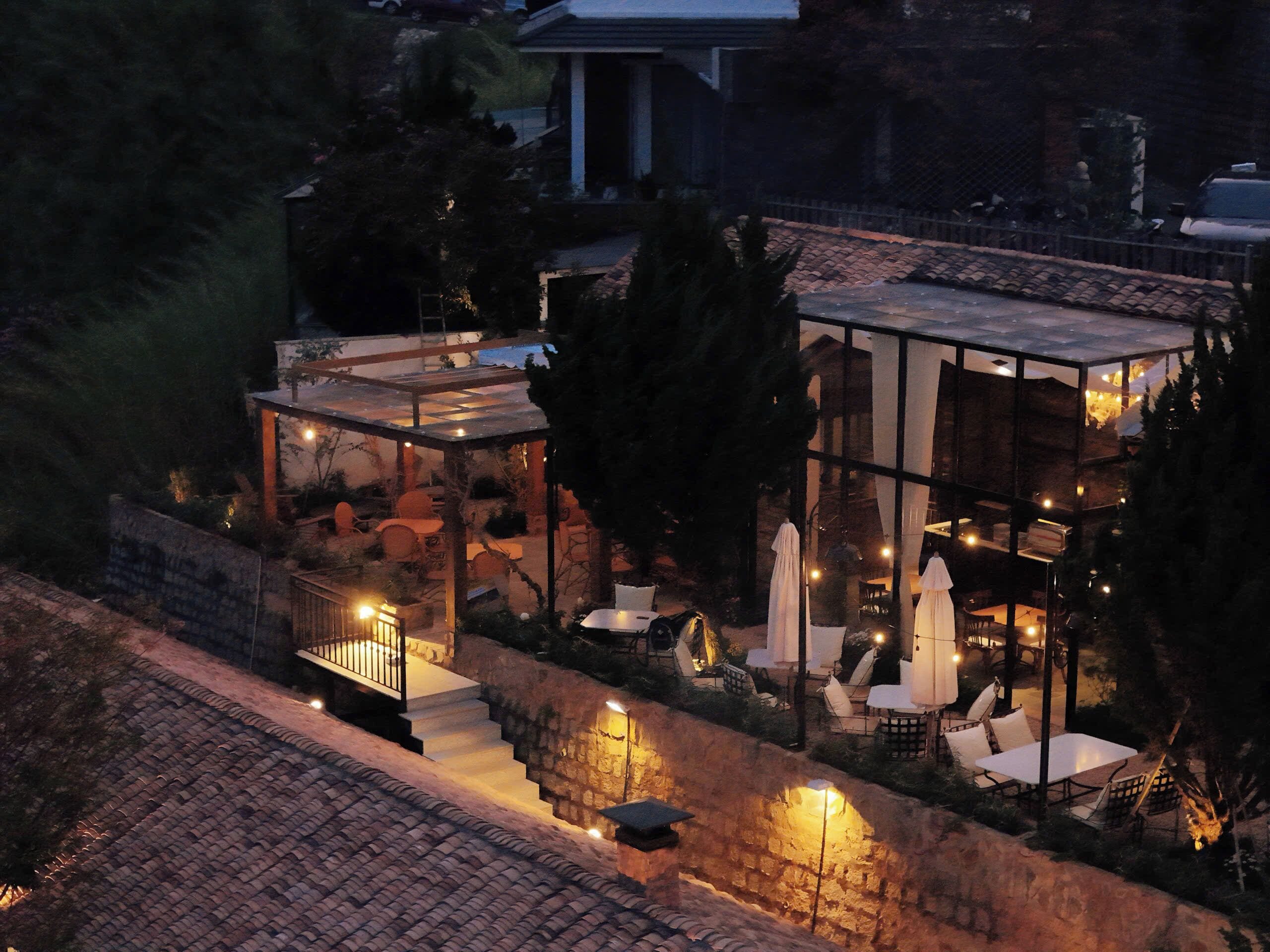 A modern house with a glass conservatory, stone walls, and outdoor seating.