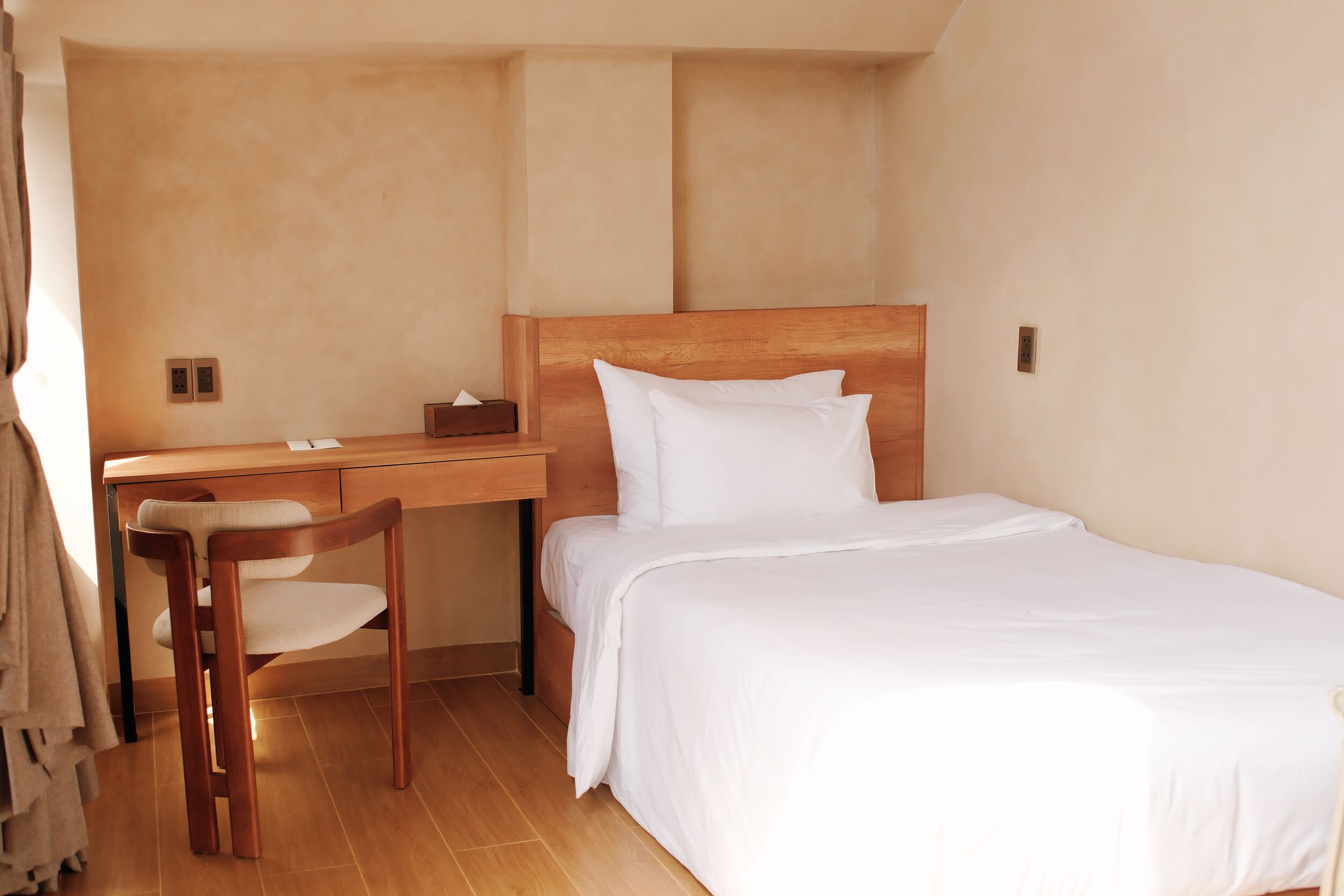 A bedroom with a wooden bed, a desk, and a chair.