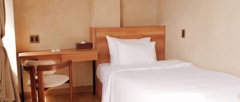 A bedroom with a wooden bed, a desk, and a chair.