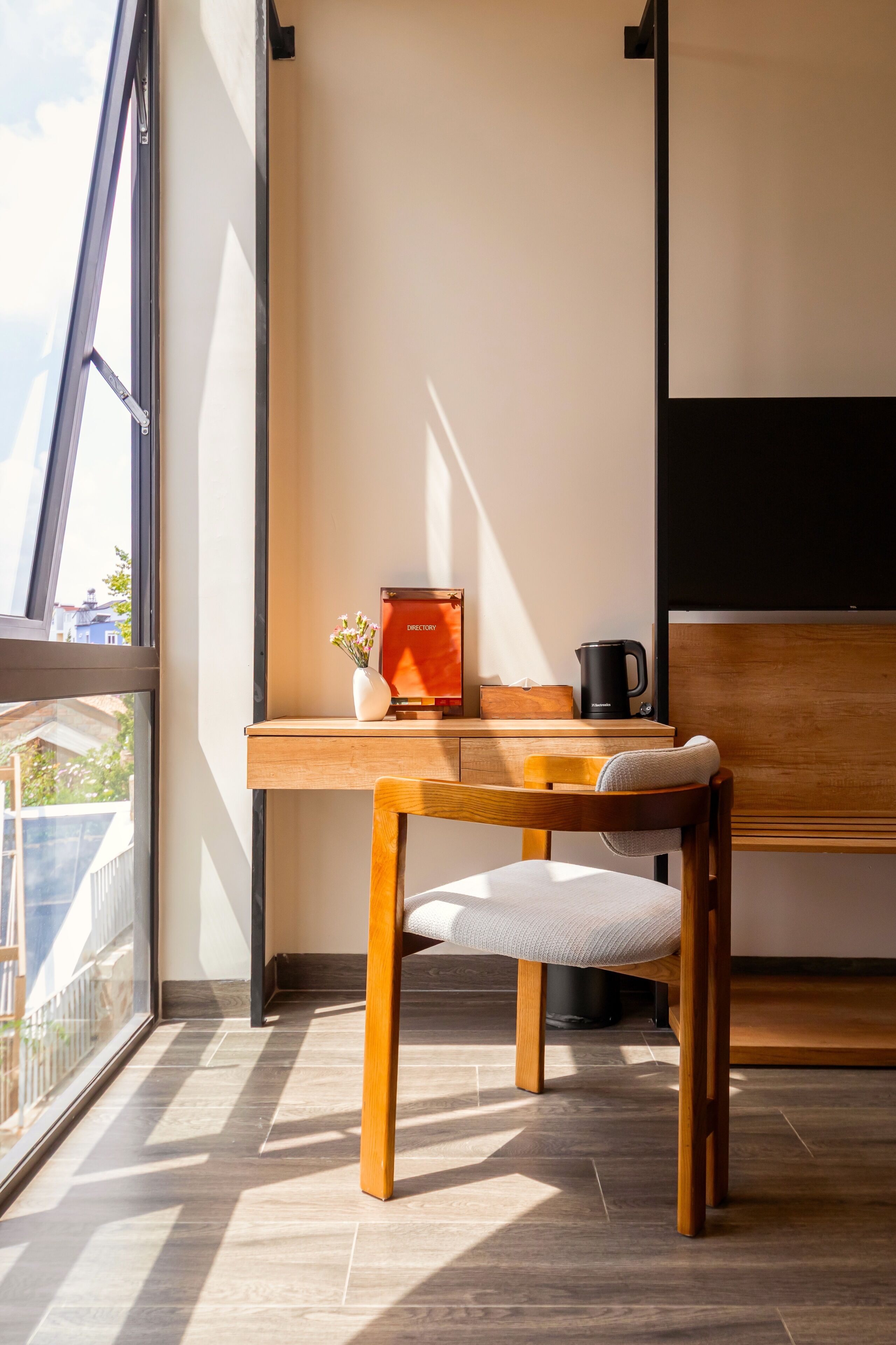 A modern room with a wooden desk, a chair, a coffee maker, and a framed picture on the wall.