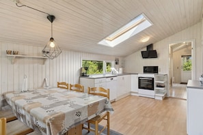 Una cocina moderna con comedor, pisos de madera y tragaluz.