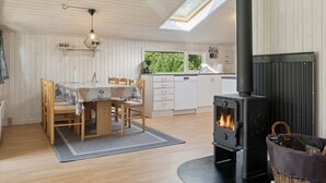 A cozy kitchen with a wood-burning stove, wooden dining table, and a skylight.