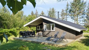 A wooden cabin with a patio, outdoor seating, and a chimney.