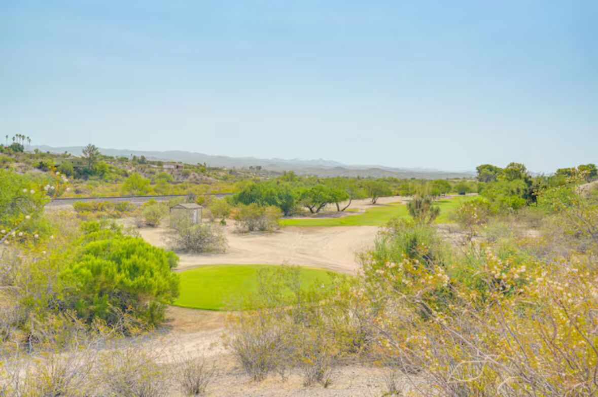 A golf course with green fairways, sand bunkers, and scattered trees.