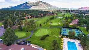 Um campo de golfe com piscina, rodeado por áreas residenciais e montanhas ao fundo.