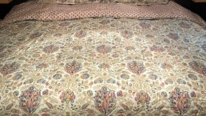 A bed with a patterned bedspread and two pillows, under wooden cabinets. - Branson Glamping - all set up for you (Branson)