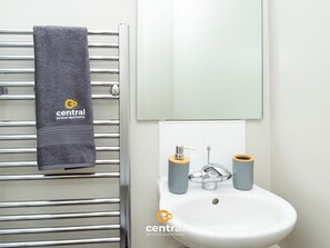 Un bagno con porta asciugamani, lavandino e specchio. L'asciugamano presenta un logo e della scritta.