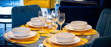 A dining table set with white bowls, wine glasses, and yellow placemats.