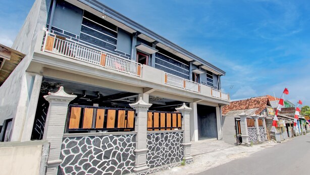 A two-story building with a balcony, a stone wall, and a tiled roof. - OYO 3220 Samudra Guesthouse (Depok)