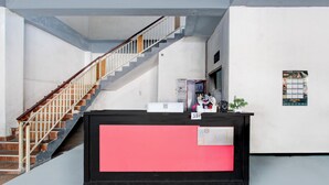 A reception area with a staircase, a reception desk, and a wall calendar. - OYO 3220 Samudra Guesthouse (Depok)
